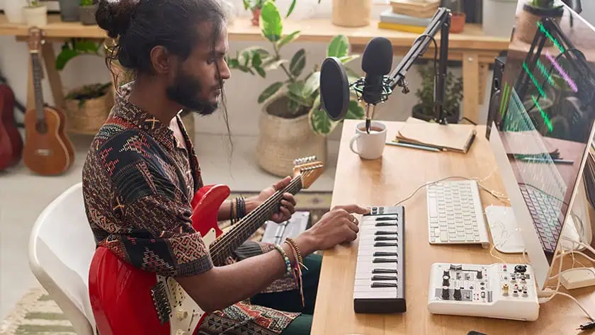 A musician adjusting audio equipment and implementing a music career action plan at a studio workspace