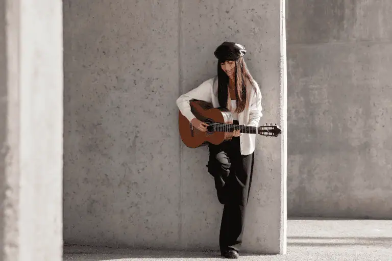 Independent musician performing at small venue demonstrating direct fan relationship model that enables £500-625 monthly Patreon income from 100-125 supporters, contrasted with label artists relying on advances with 80/20 revenue splits and label-controlled masters