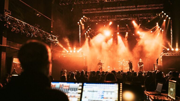 A sound engineer at a live concert mixing desk, illustrating how music management works as amplification rather than creation.